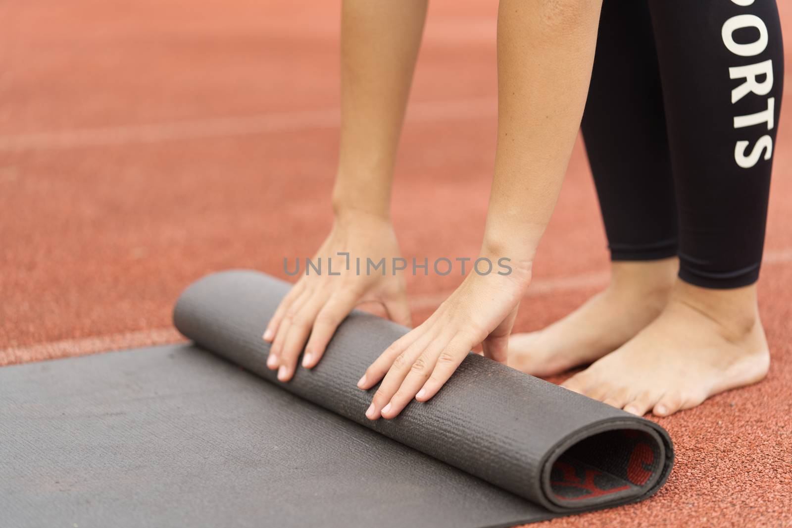 Young woman rolls away the mat for yoga and exercise.