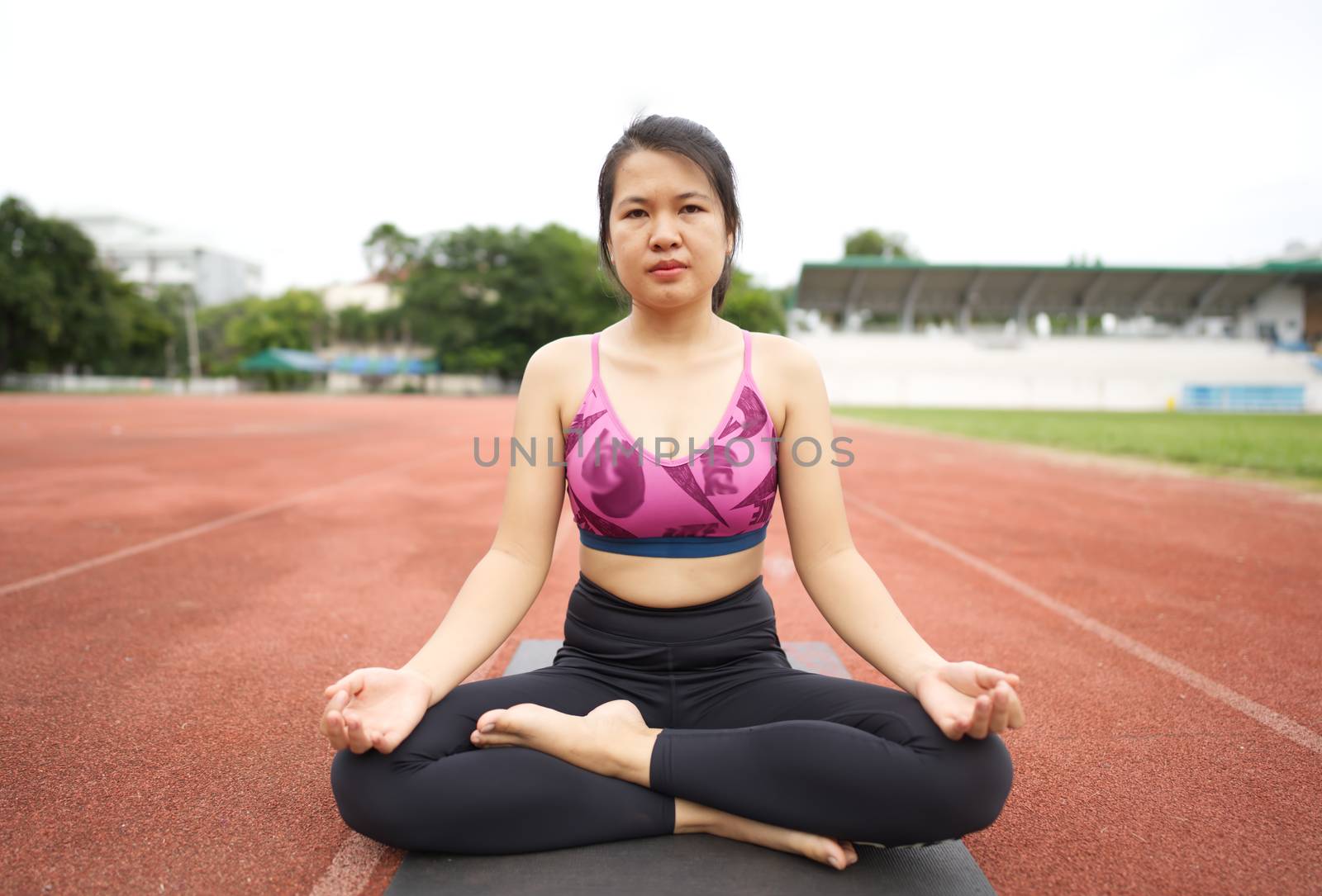 Asian young women doing yoga, stretching for a healthy body, healthy body at the outdoor sports stadium.