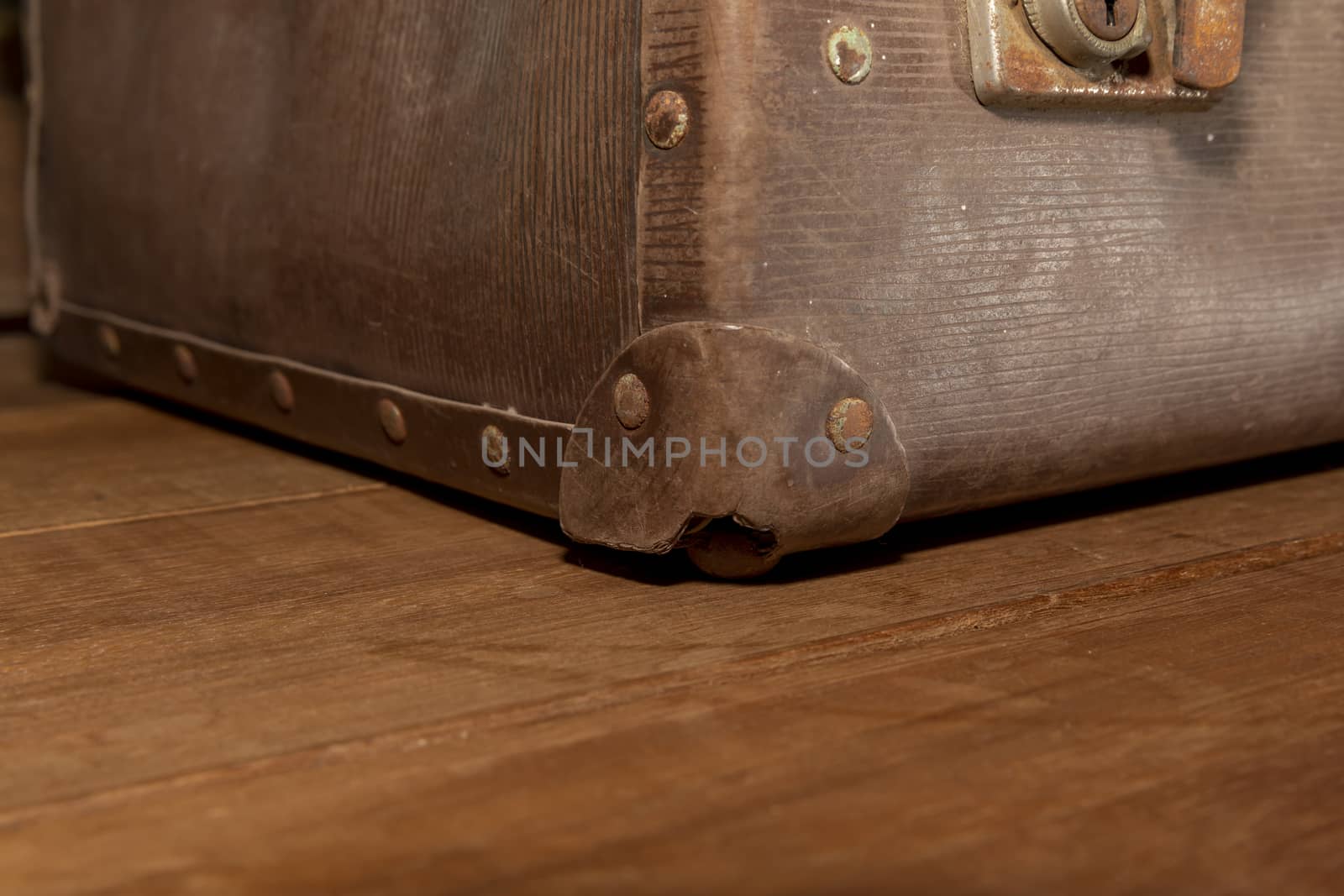 A damaged corner protector on an old brown leather suitcase