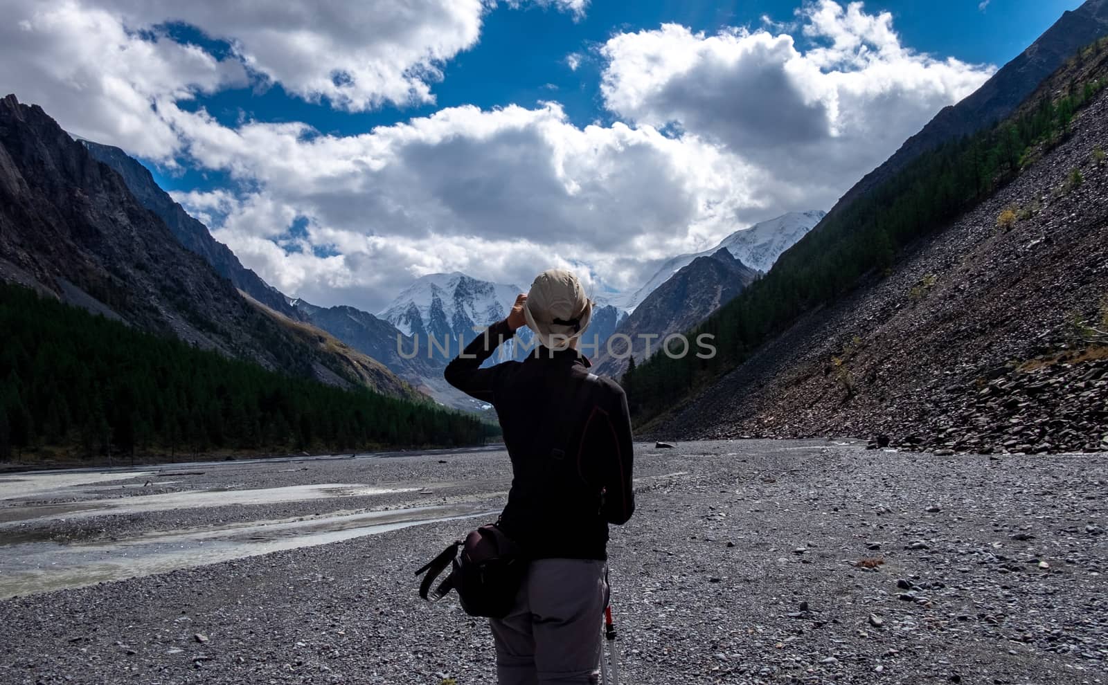 A girl in a cowboy hat looks at the mountain landscape in the Altai Republic.