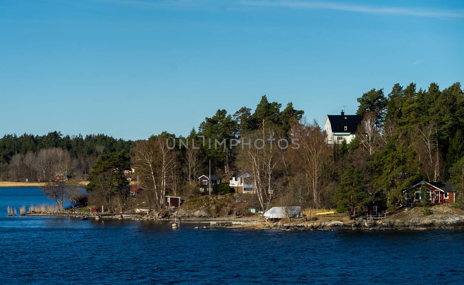 Picturesque summer houses painted in traditional falun red on dwellings island of the Stockholm archipelago in the Baltic Sea in the early morning.