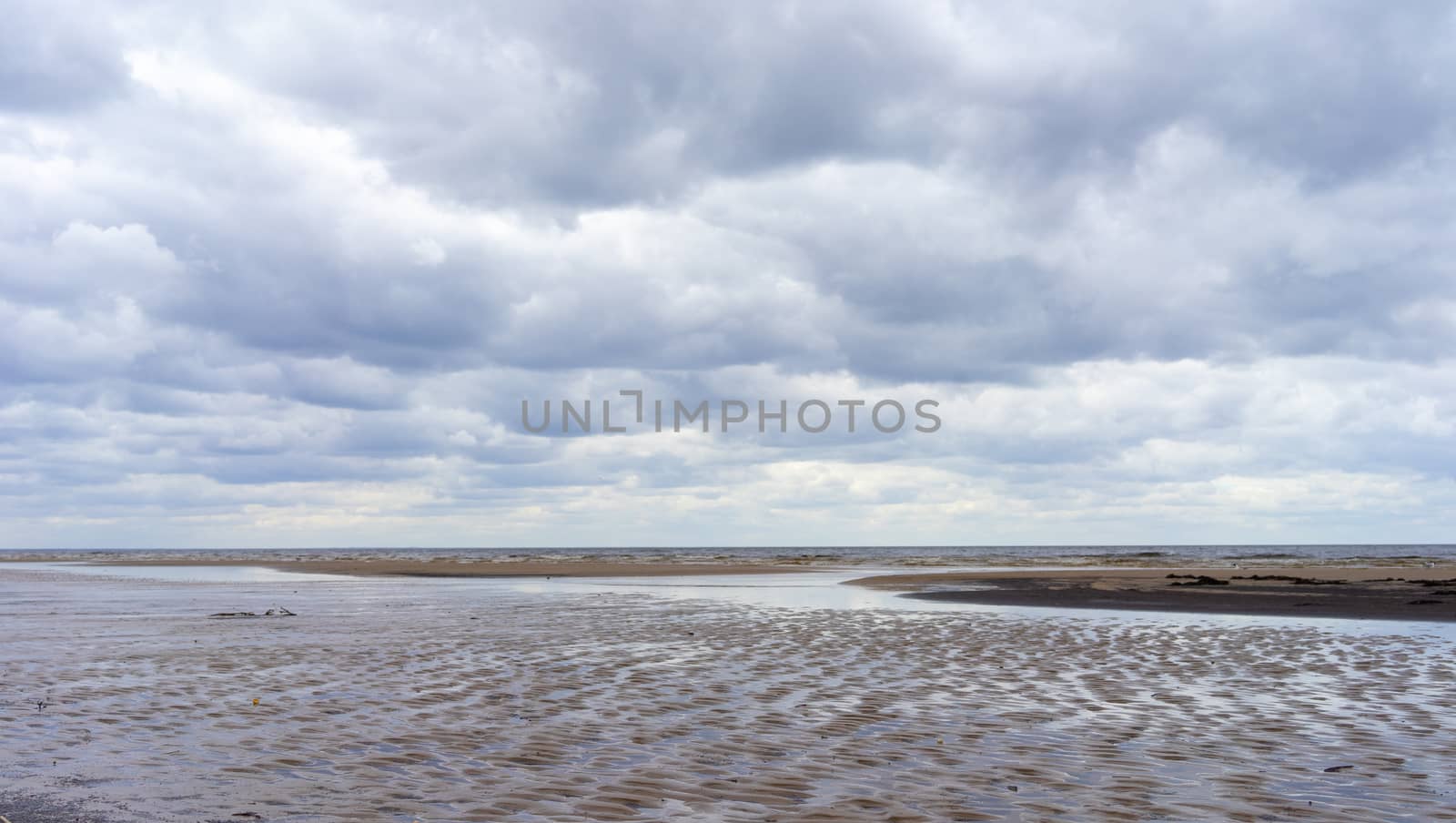 Reflection of clouds in a small lehman on the sandy shore of the Baltic Sea in Jurmala in cloudy weather.