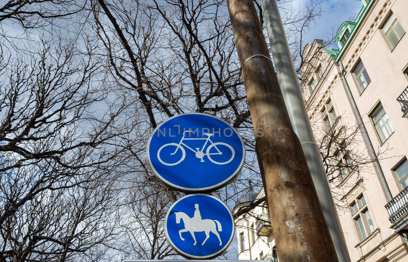 Blue road signs a road for cyclists and a road for riders on a street in Stockholm.