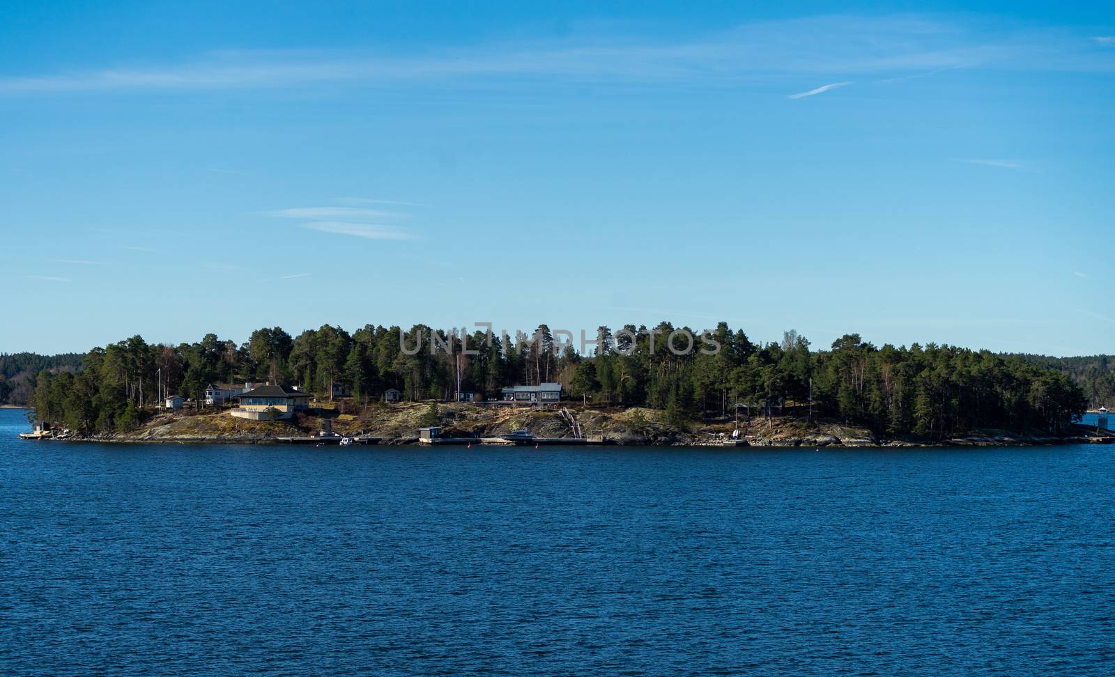 Picturesque summer houses painted in traditional falun red on dwellings island of the Stockholm archipelago in the Baltic Sea in the early morning.