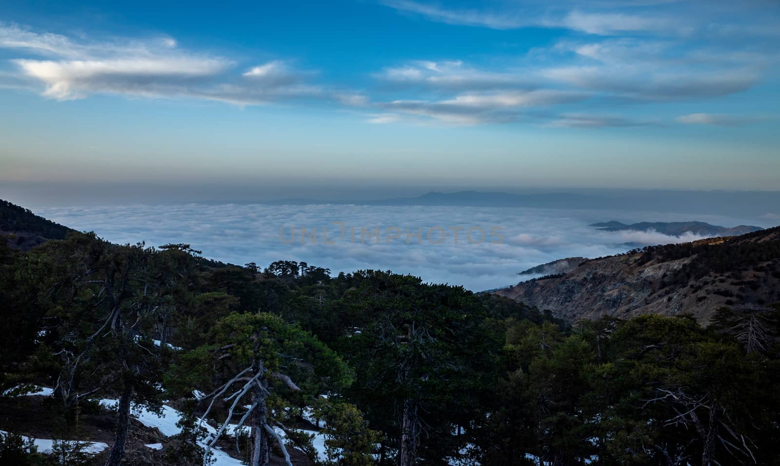 View of the blue fog over a mountain valley in clear sunny weather from the top of the mountain.
