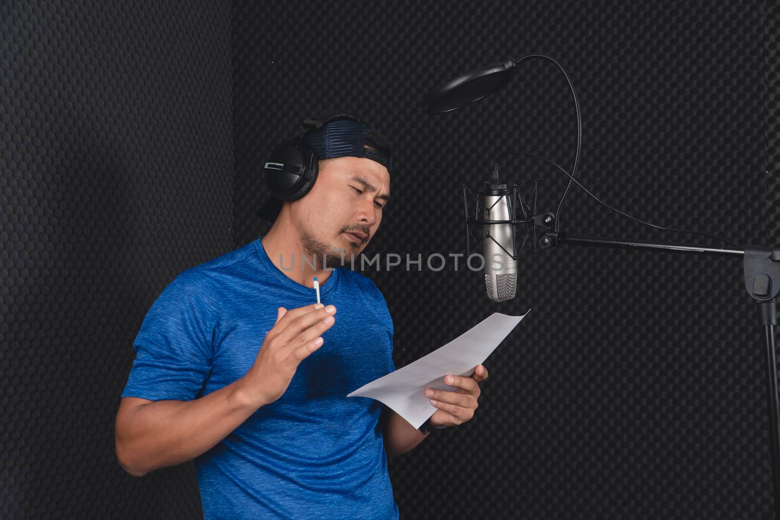 Confident Asian mature young man and a microphone Practice singing in the recording studio. Artist audition for media, music, and performance producer.