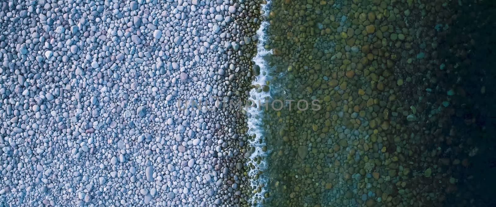 Coastline, sea wave goes ashore of stone and pebbles.