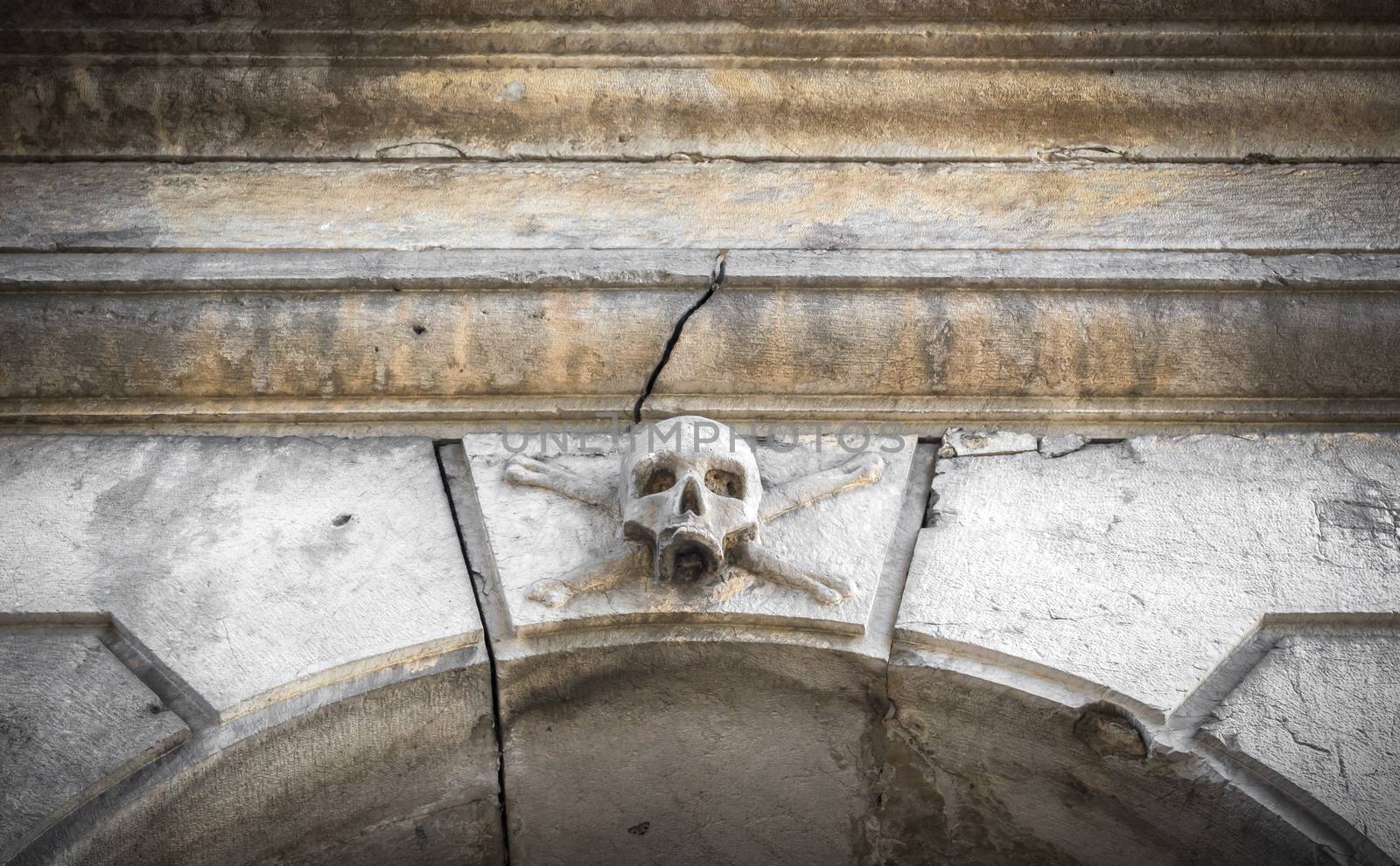 A stone skull placed near the entrance of a charnel house, in an Italian graveyard.