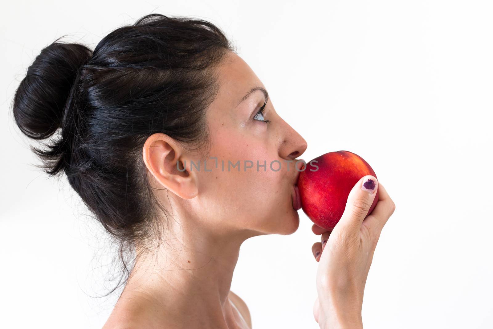 A girl while eating a peach, isolated on white background.