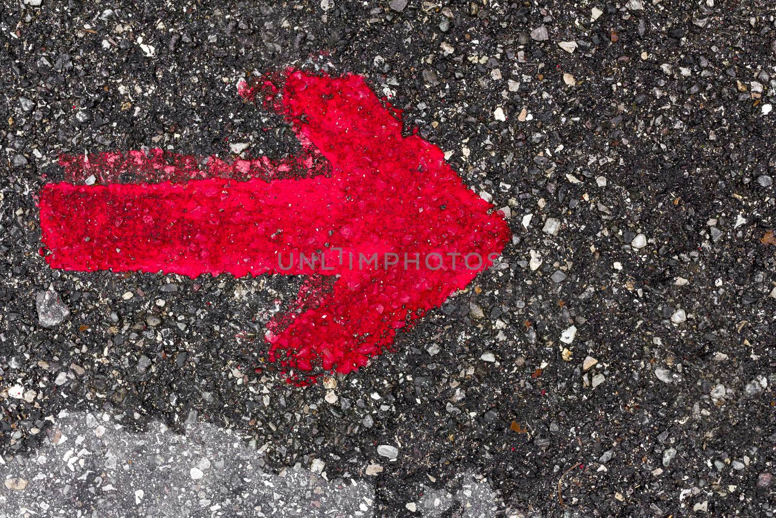 A red arrow pointing to the right, painted with red paint on the asphalt.
