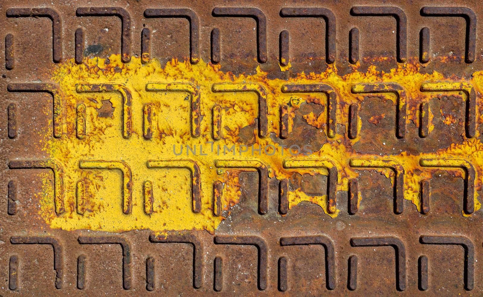 Relief pattern of rusty manhole cover in closeup with rust stain.