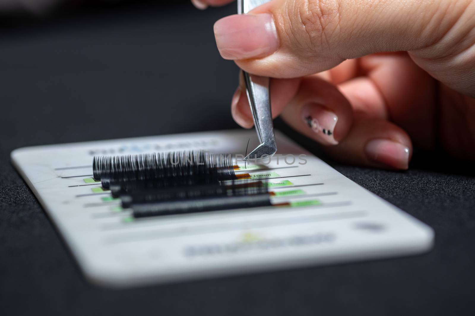 Master hand takes accessories with tweezers tools for eyelash extension.