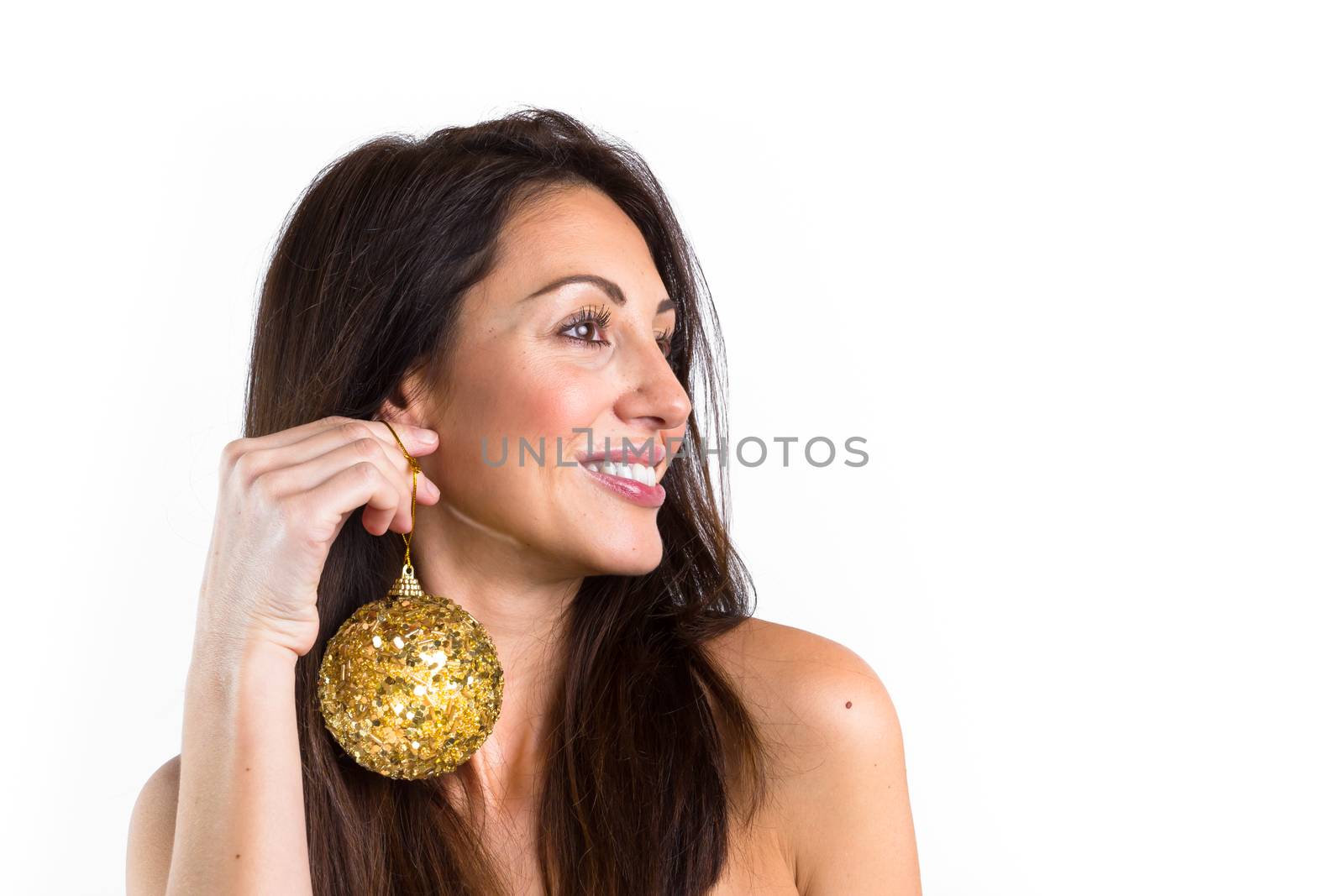 Atracctive young woman holds a golden Christmas ball as earring. Christmas and decor concept.