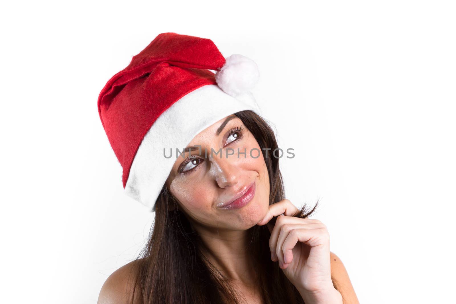 Woman with brown hair and Santa Claus hat on her head, smiling thoughtfully.