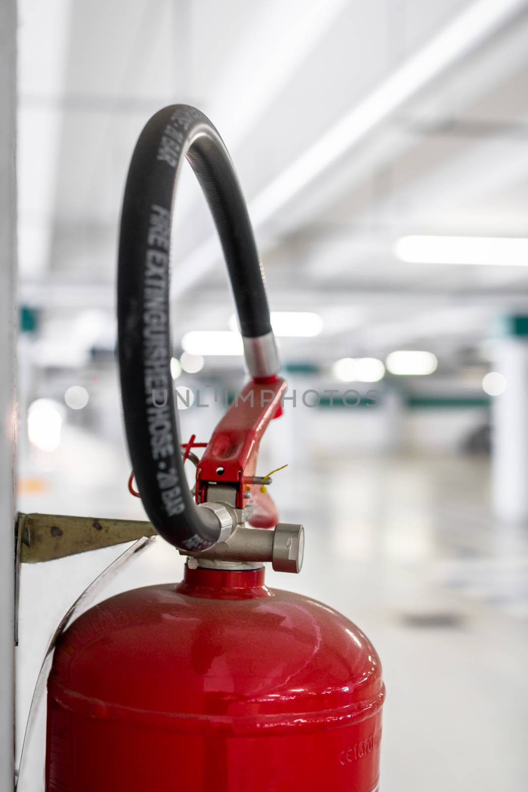 Extreme close-up of a fire extinguisher placed on the column of a car park