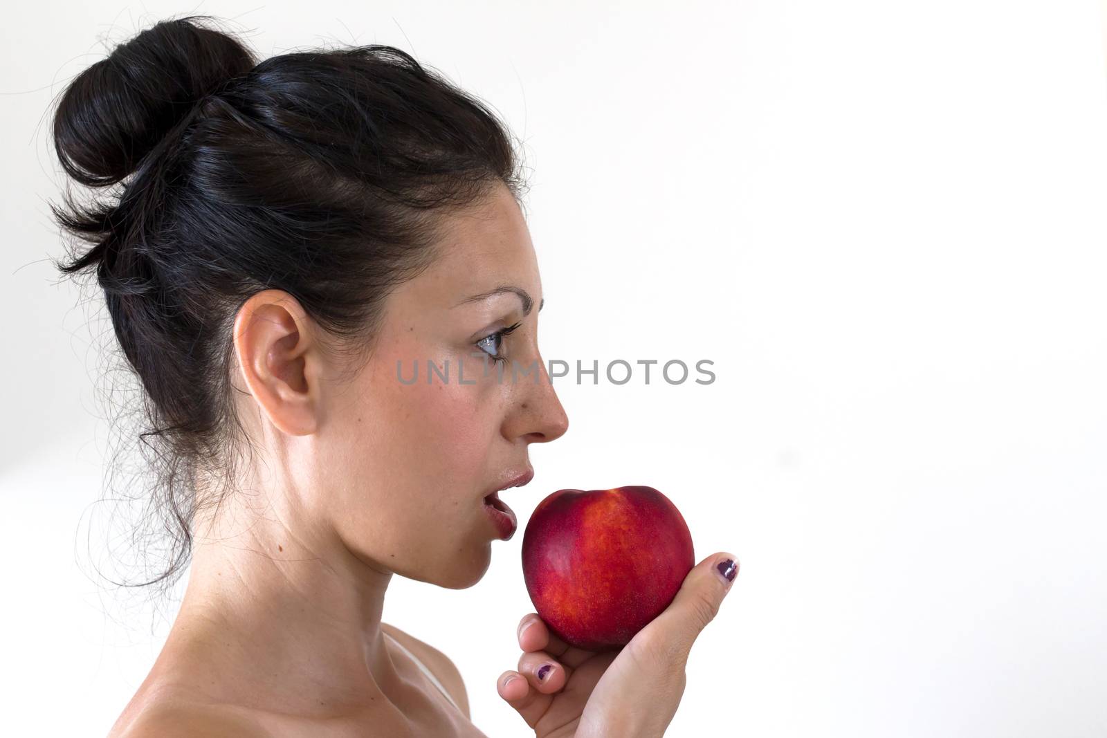 A girl while eating a peach, isolated on white background.