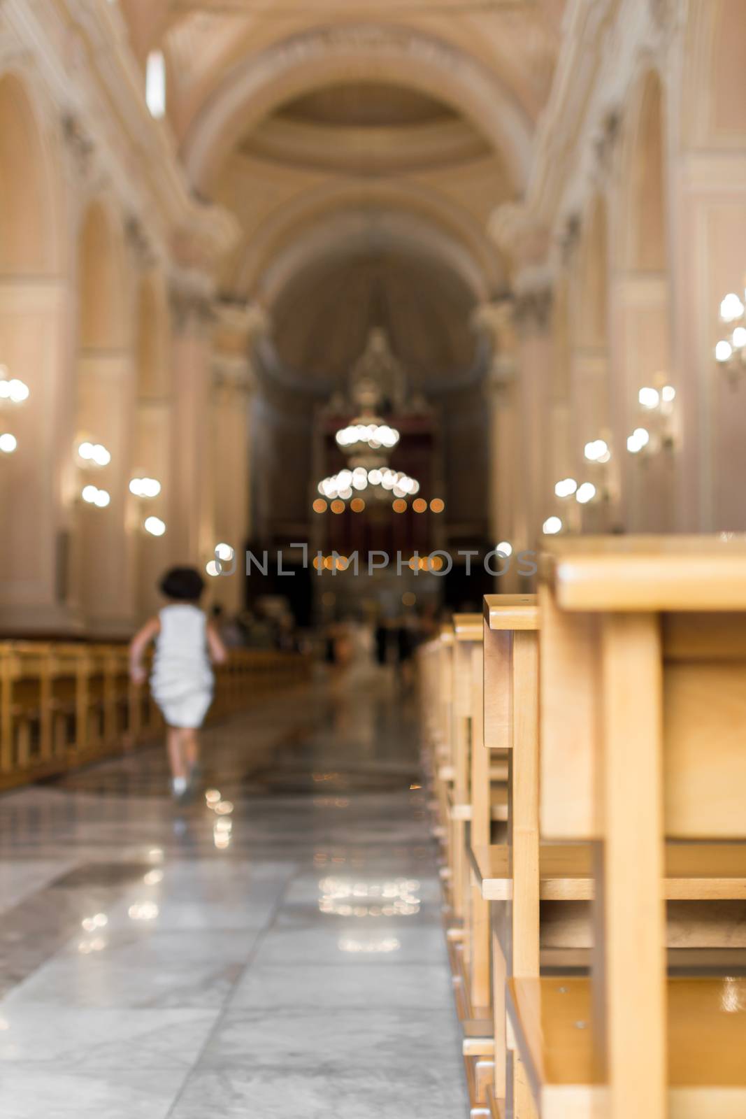 A little girl runs in the nave of a church, to the altar.