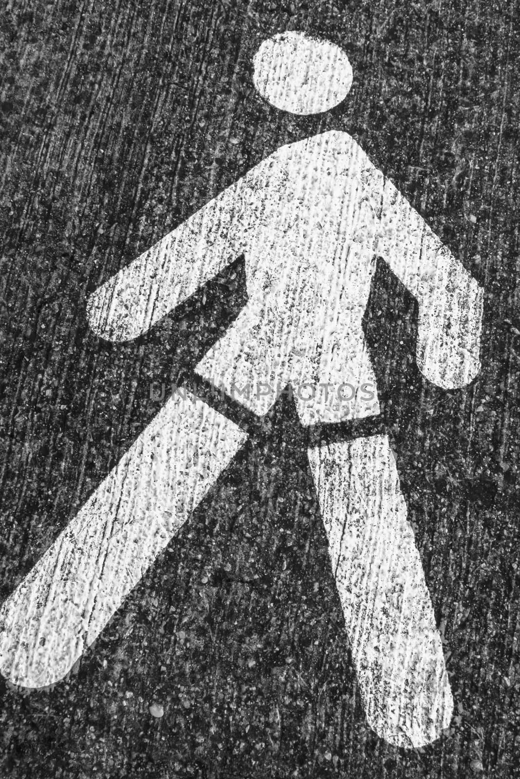 White Pedestrian Symbol on the gray asphalt. Roadsign.