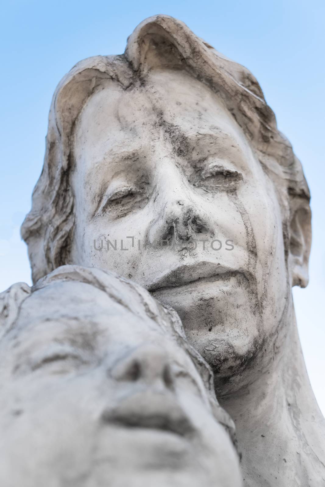 Statue of a mother and son against blue sky