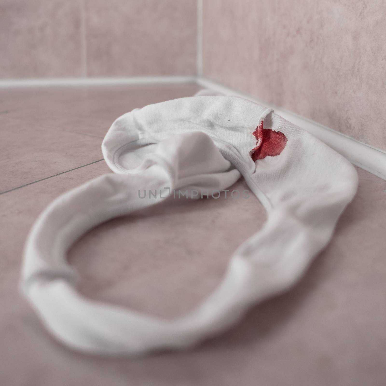 White panties in bloody stain. Beginning of the menstrual cycle. Signal of the transition from girl to woman. Selective focus.