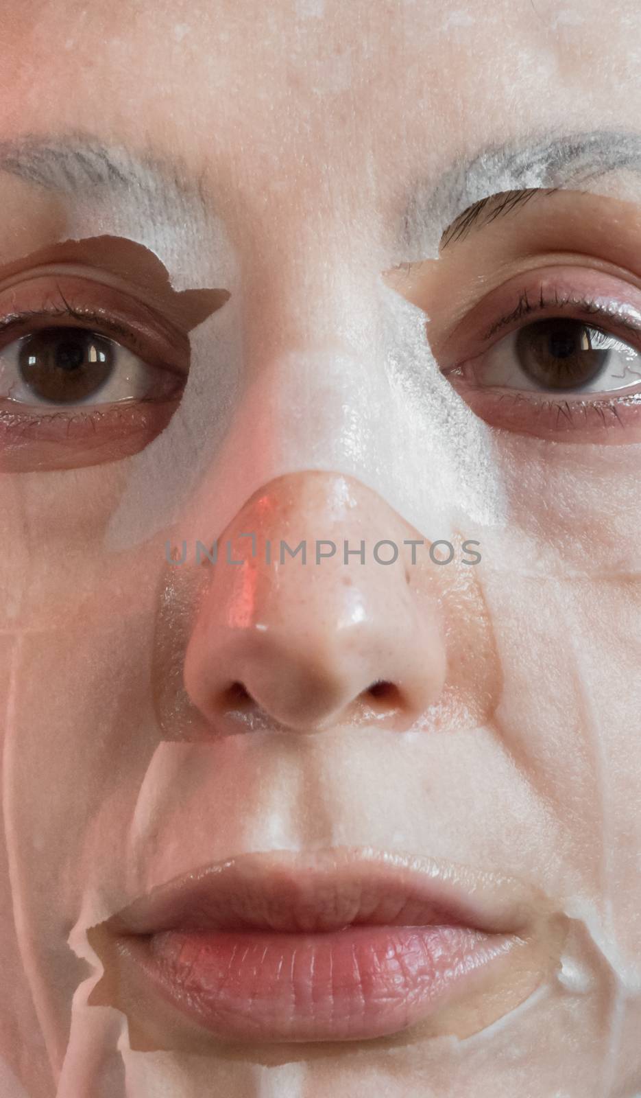 Woman portrait with a face mask sheet white. Beauty, youth, skin care.