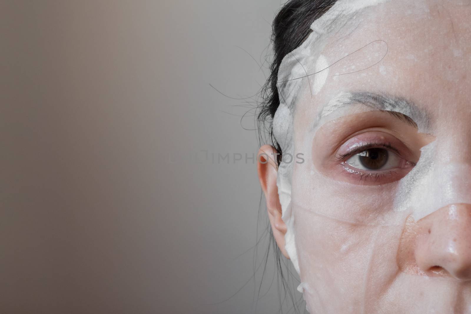 Woman with a face mask sheet white. Beauty, youth, skin care.