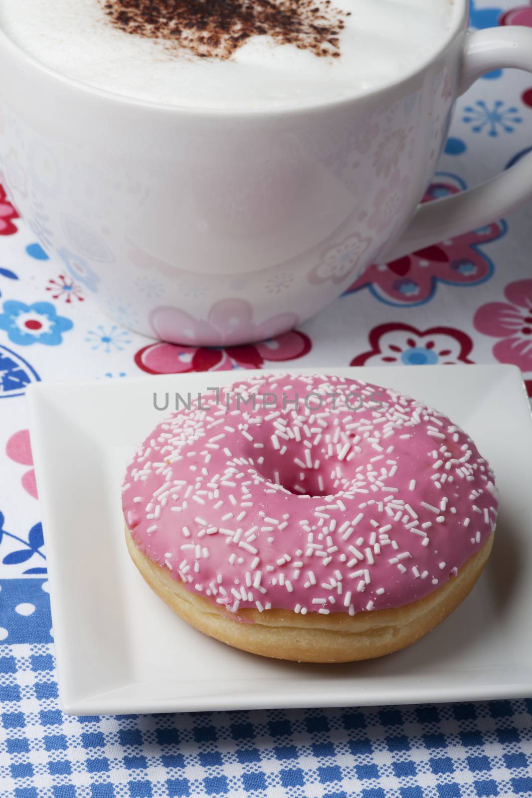 pink donut and a cup of cappuccino
