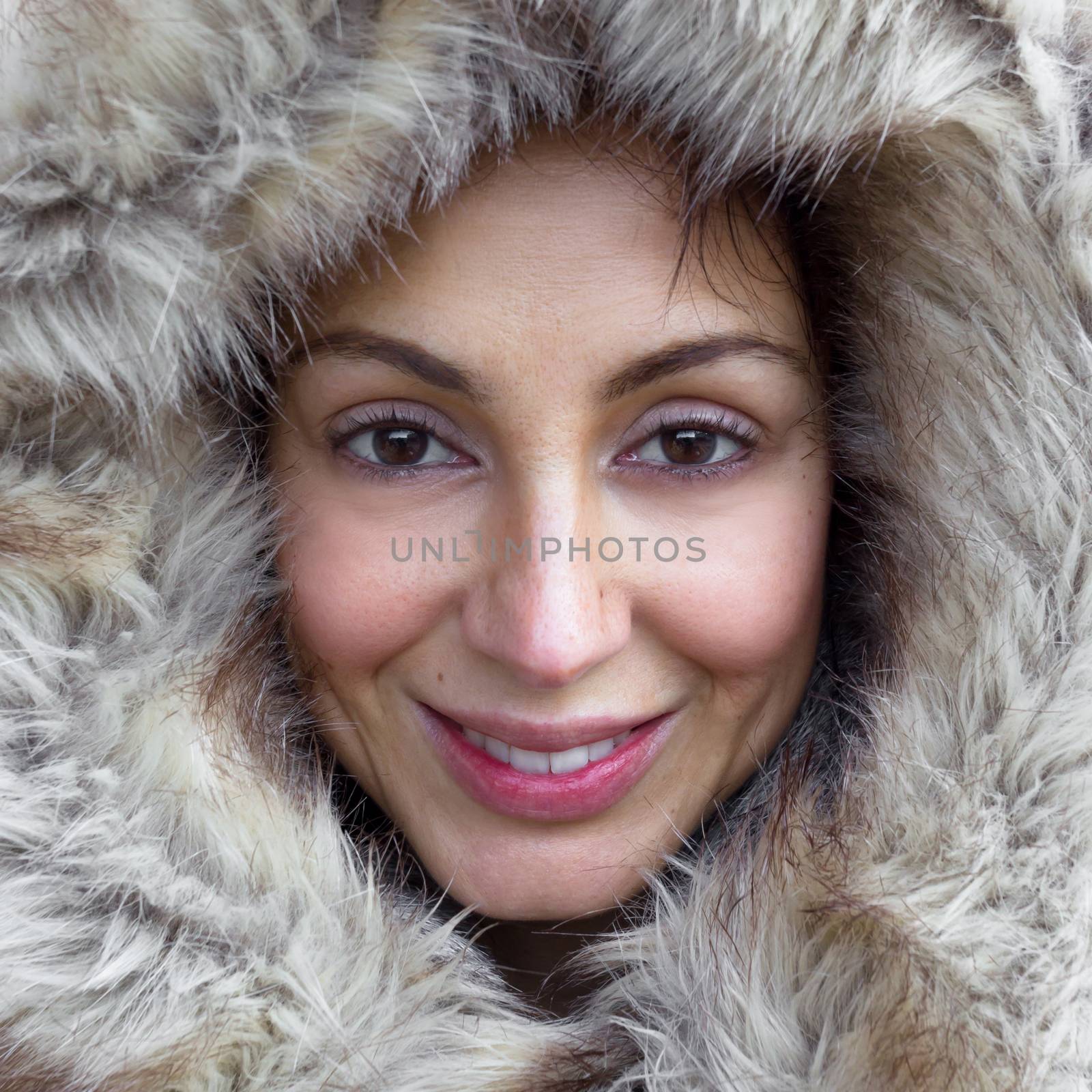 Closeup portrait of cute woman wearing warm coat with hood with fur, having fun in winter park, wintertime fashionable style, vacation concept.