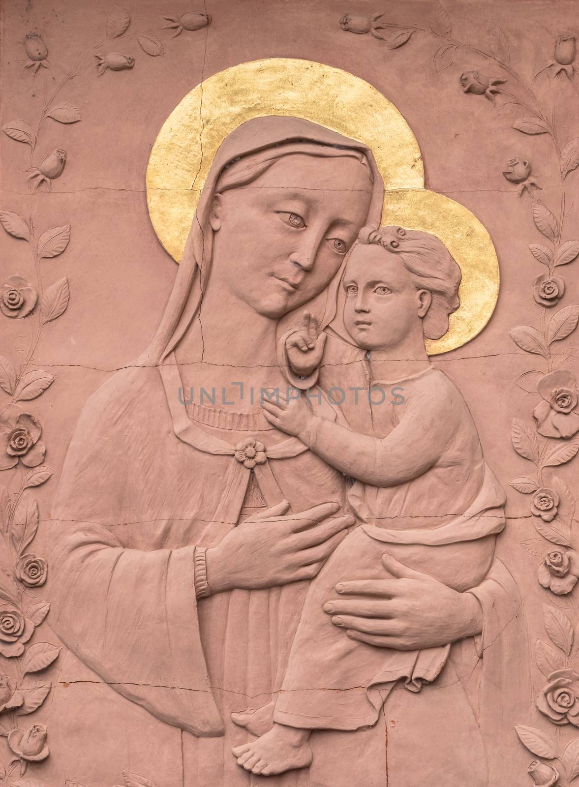 Sculpture in Bas - relief in red stone of Mary and baby Jesus, with golden crowns. Ideal for concepts, events and backgrounds.