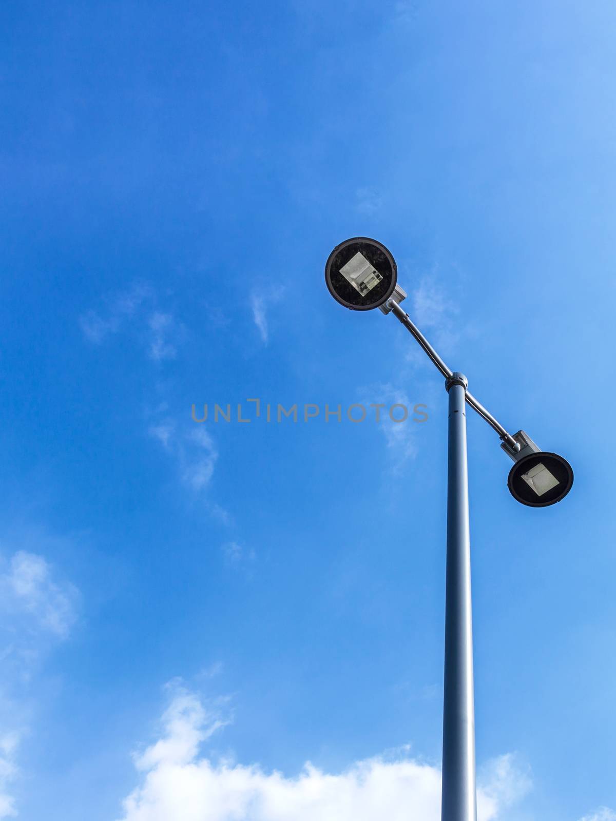 Street light pole over blue sky with clouds. Copy space.