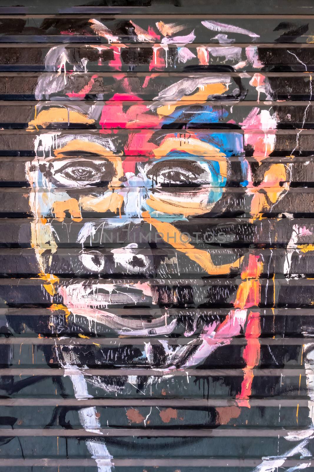 Graffiti with face of ethnic man on the old door of garage. Unknown artist. Bergamo, ITALY - May 06, 2019.