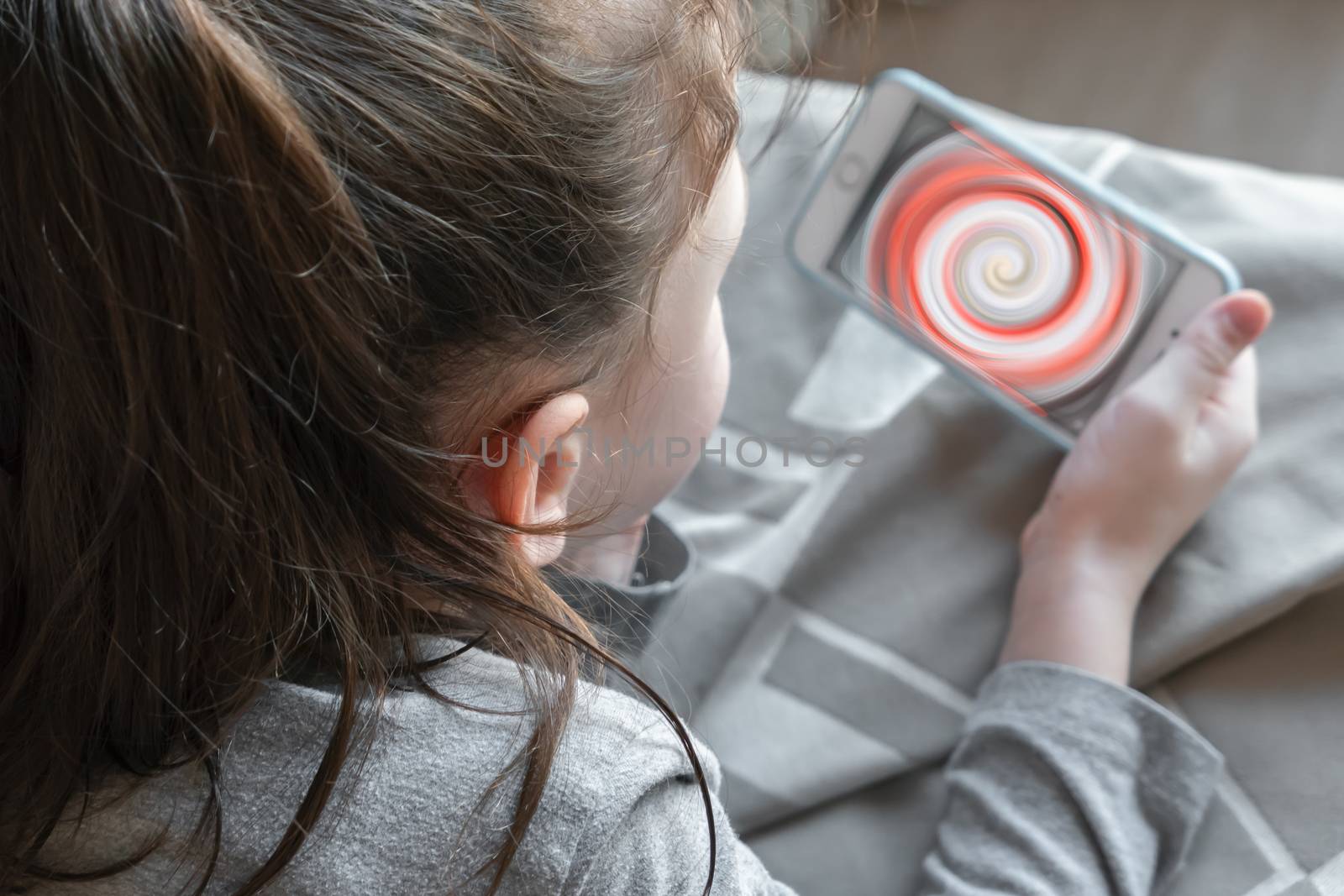 Cute young child watching screen of smartphone closely. Digital device addiction, childhood and education. Shallow dof.