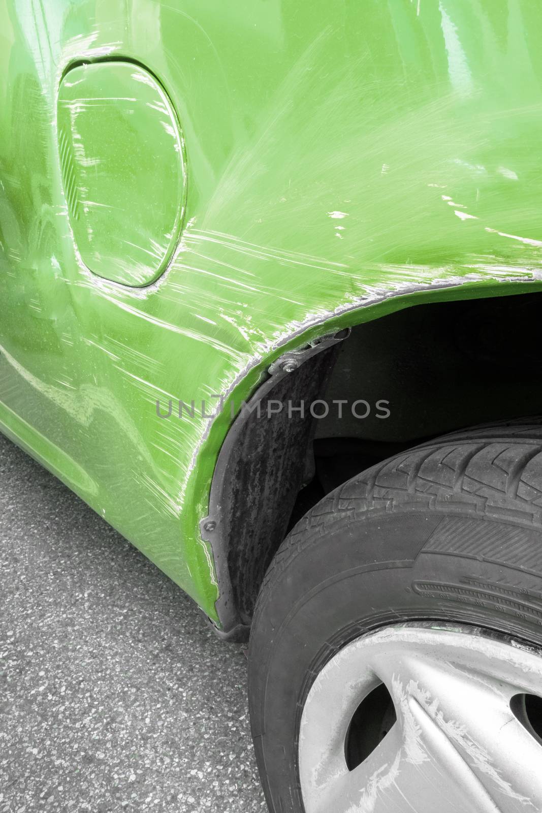 Generic green car with scratched paint and dented body in crash accident or parking lot.