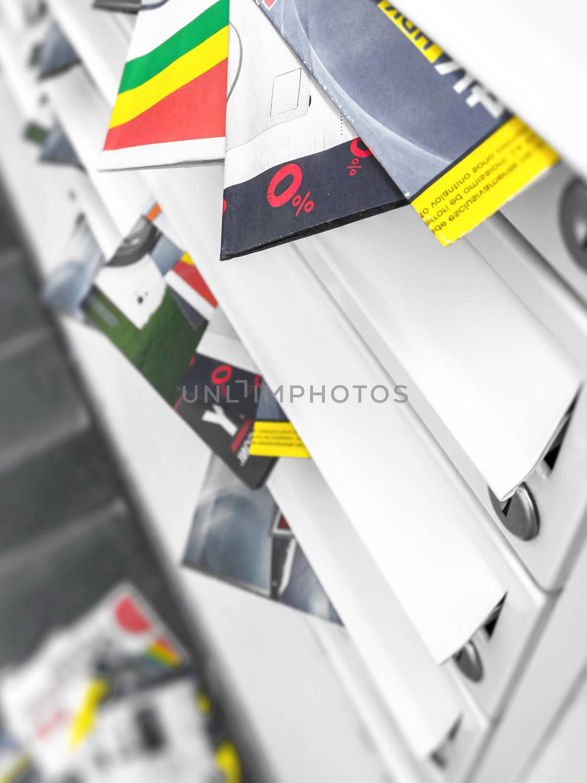 Metal mail boxes, overfull of leaflets; some have fallen on the ground. Ideal for concepts. Shallow DOF.