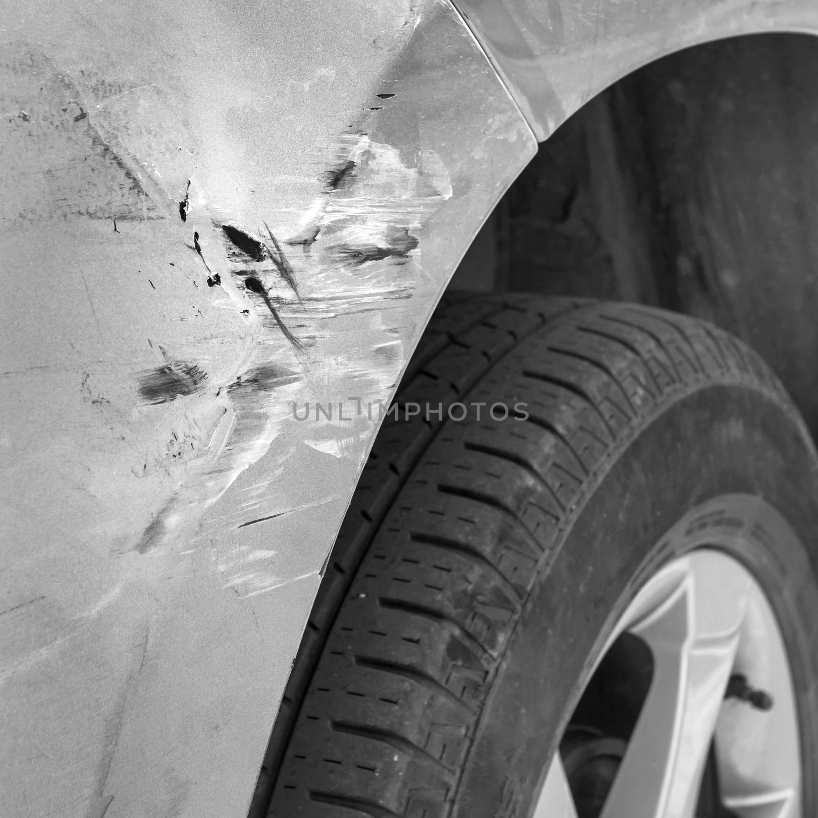 Generic car with scratched paint and dented body in crash accident or parking lot. Close-up.