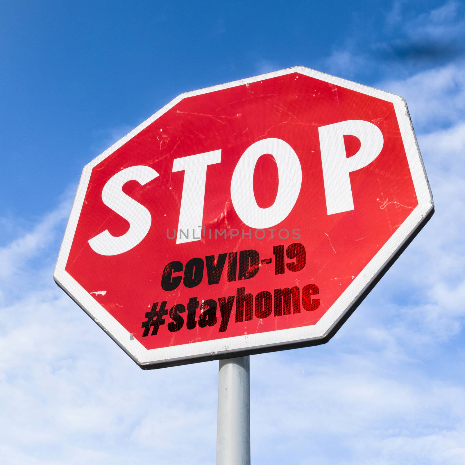 Grungy stop sign with hashtag #stayhome (COVID-19) on sky background. Coronavirus in Italy. COVID-19 alert banner. 2019 Coronavirus concept for an outbreak occurs in Wuhan - China.