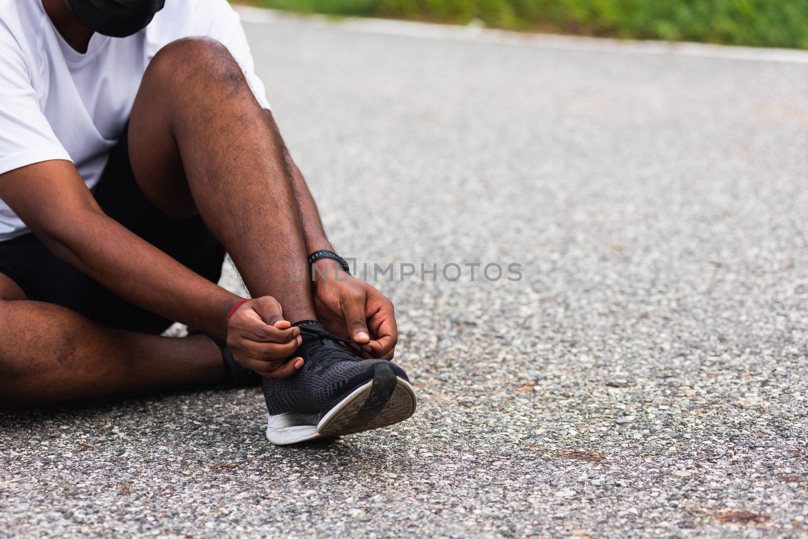 Close up Asian sport runner black man sitting shoelace trying running shoes getting ready for jogging and run at the outdoor street, health exercise workout concept