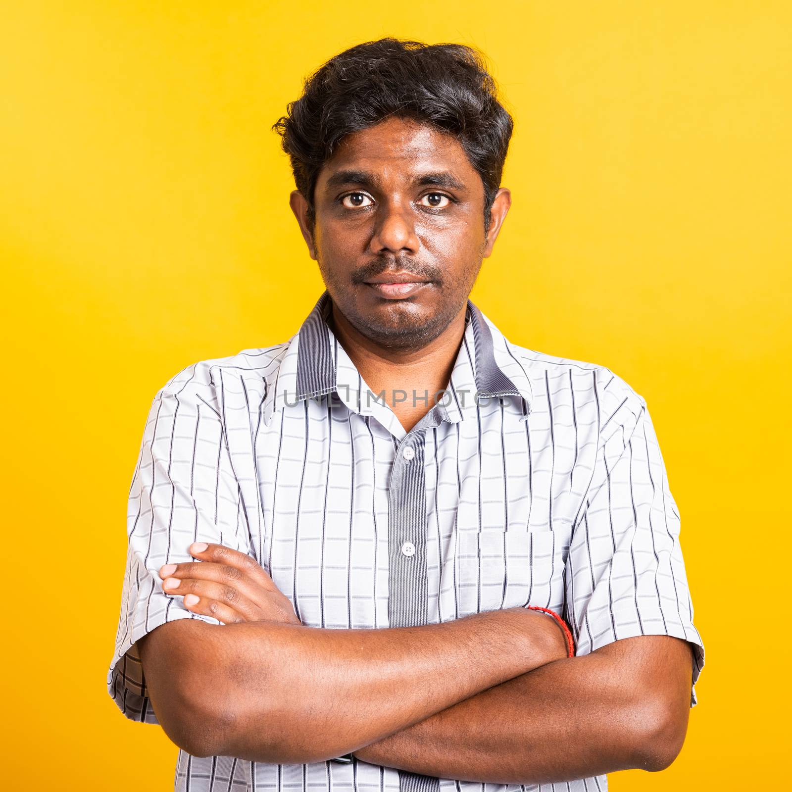 Closeup Asian happy portrait young black man standing cross arms chest confident pose and looking camera, studio shot isolated on yellow background