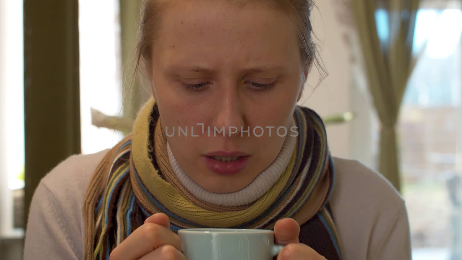 Close up portrait of sick woman drinking hot tea. Natural influenza treatment. Cup of hot drink close up