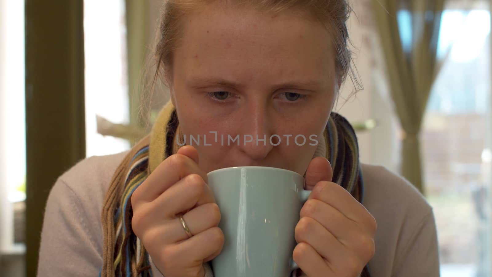 Close up portrait of sick woman drinking hot tea. Natural influenza treatment. Cup of hot drink close up