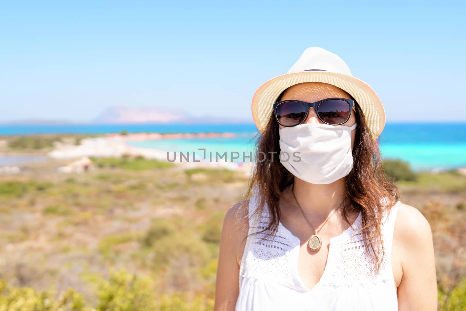 Caucasian young woman posing for a picture with Coronavirus protection mask in summer vacation with bright and colored tropical sea in the background by robbyfontanesi