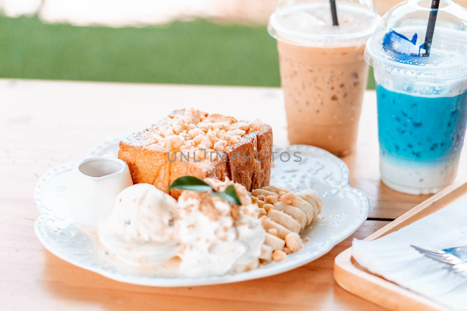 Honey toast dessert with ice coffee on wood table.