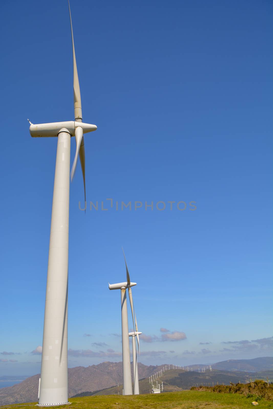 Landscape with lined up wind turbines of a wind farm on a mountain rig. Sustainable energy