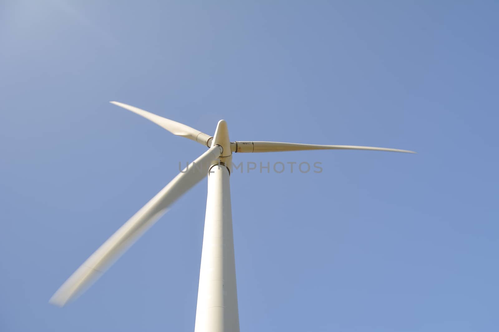 Close-up and low angle view of spinning blades of a wind turbine generating renewable energy by kb79