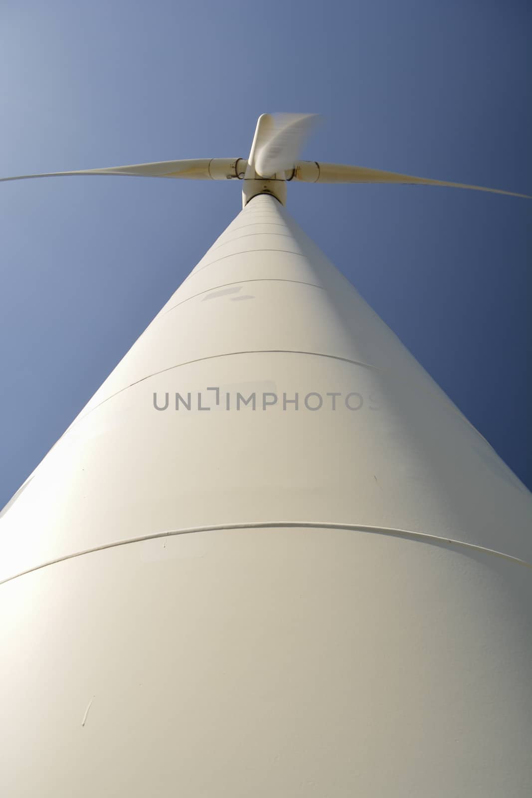 Close-up and low angle view of spinning blades of a wind turbine generating renewable energy by kb79