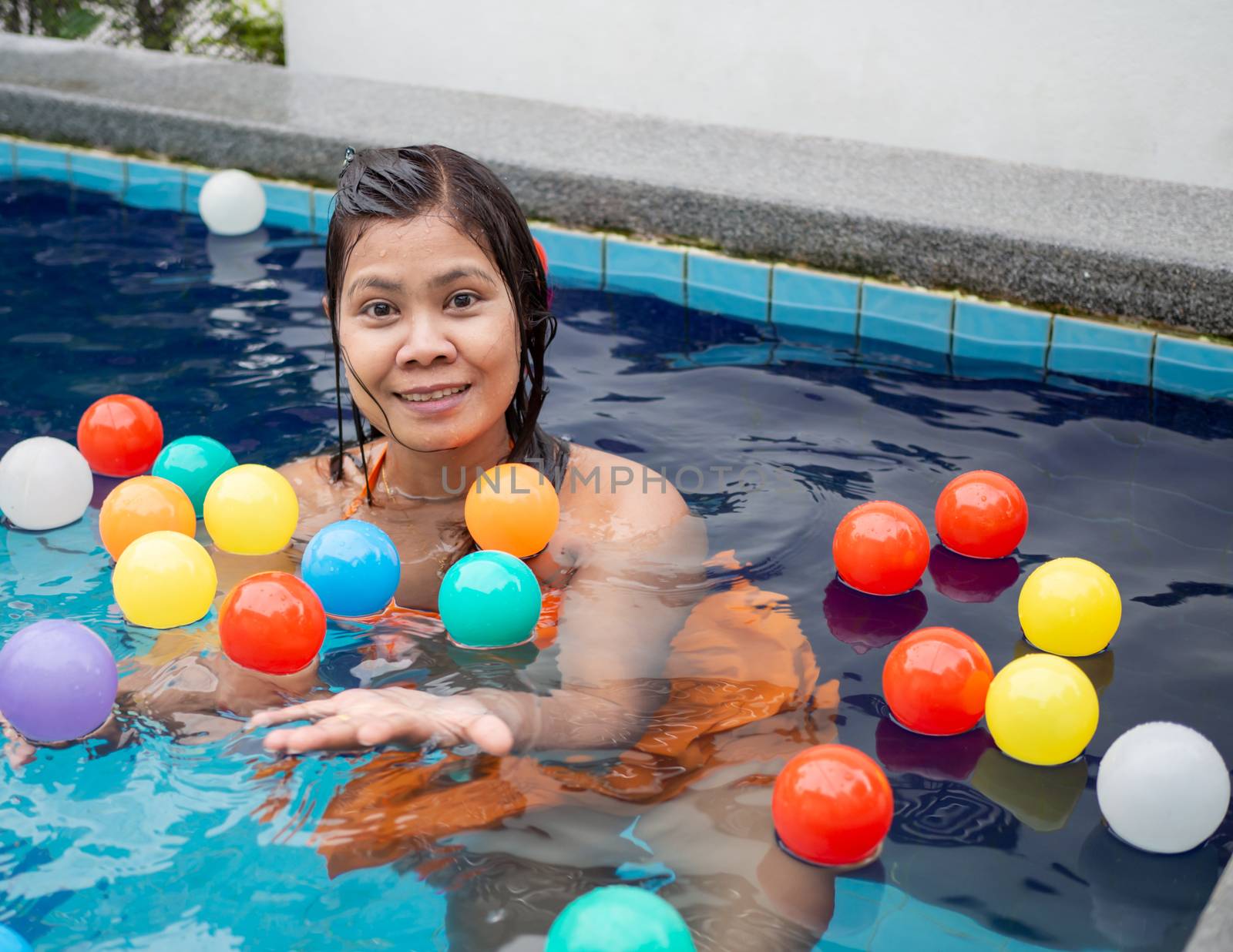 A woman playing in the ball in the pool by Unimages2527