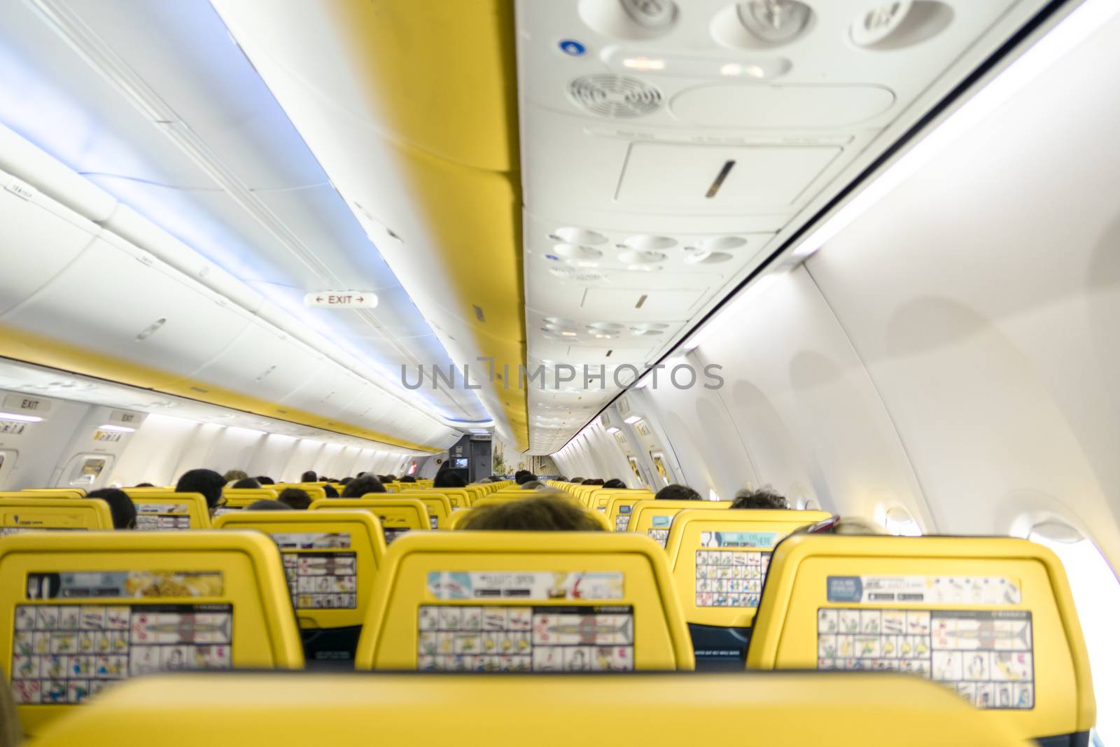 Blurred foreground. Passenger on airplane. Airplane interior with people sitting on seats.