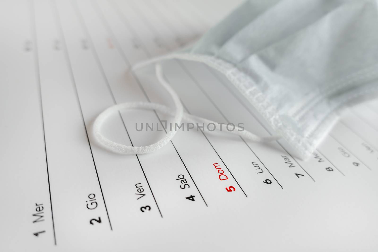 Montly calendar with self protection face mask. Coronavirus concept. Beginning / end of the pandemic. Deadline concept with sheet of monthly calendar. Coronavirus COVID-19. Copy space. Selective focus.