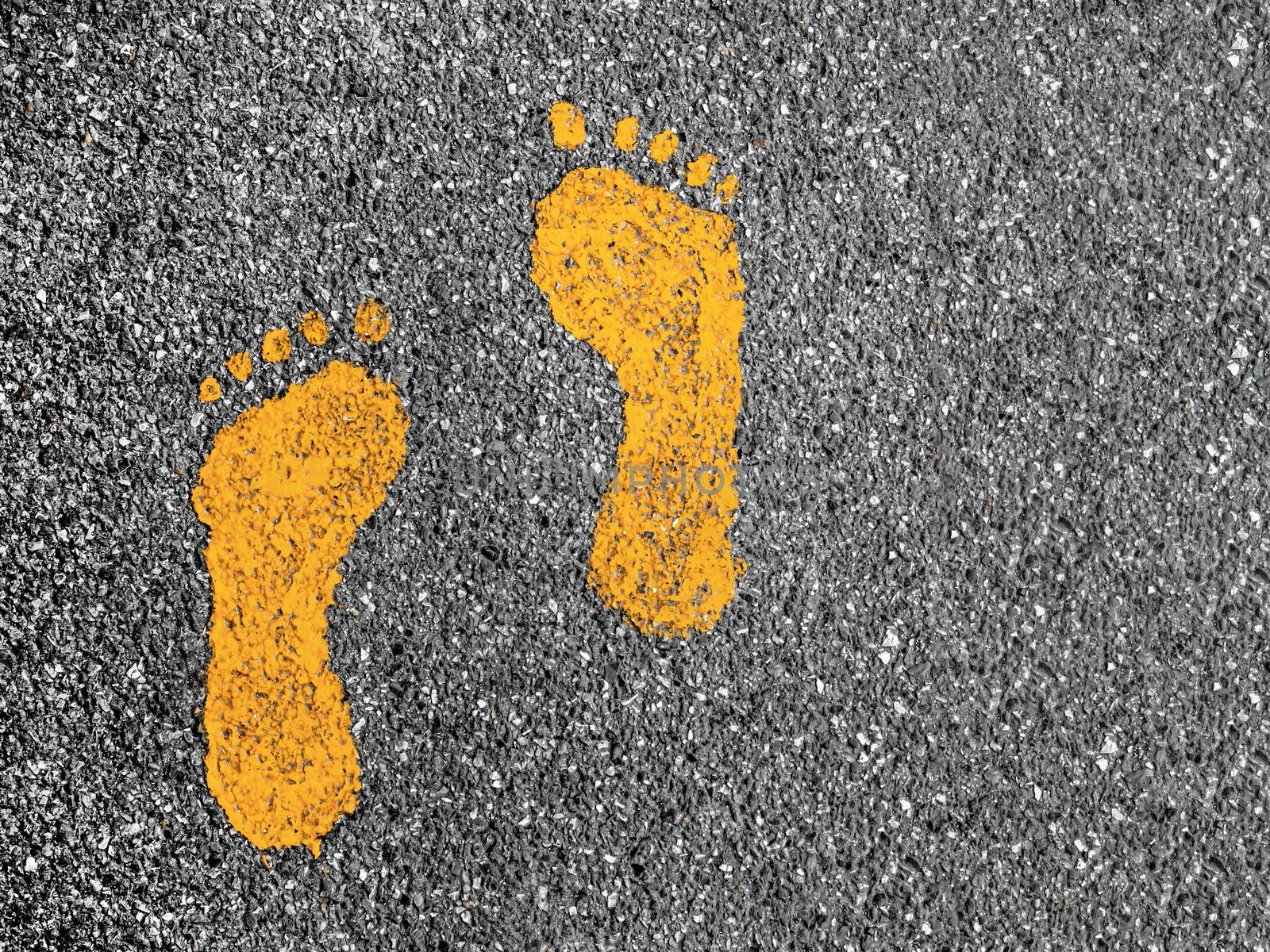 Orange footprint signs on an asphalt road for pedestrian. Symbol of walkway.