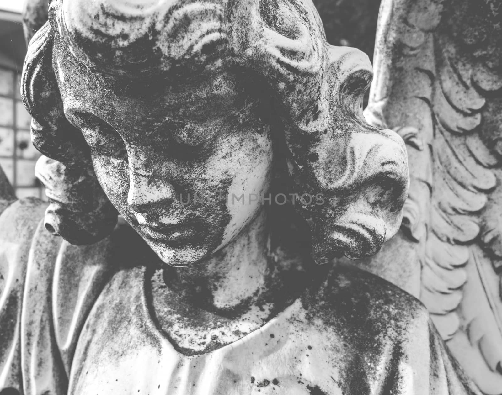 Black and white image of antique stone statue of sad angel. Retro stylized. Religion, faith, death, resurrection, eternity concept.